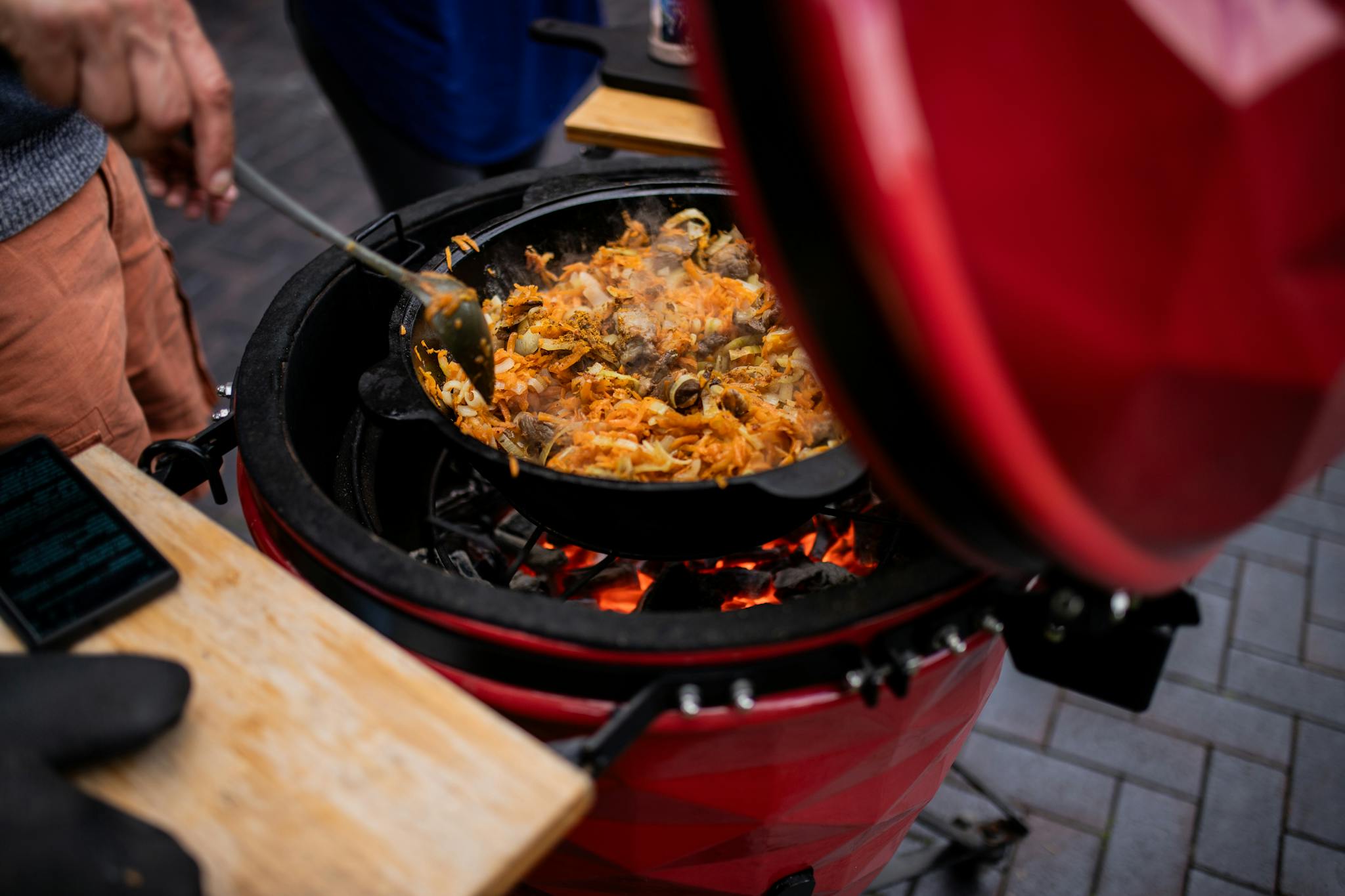 A delicious pilaf is being prepared on a kamado grill outdoors, showcasing vibrant culinary skills.
