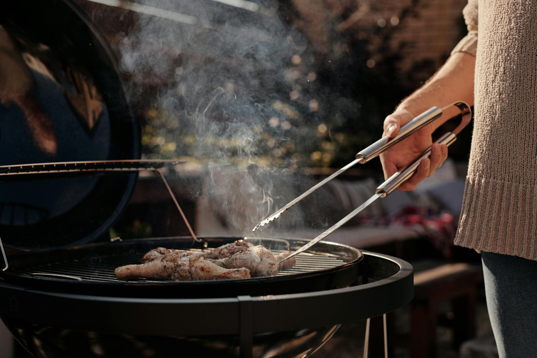 Grilling chicken on a barbecue grill outdoors, highlighting a cozy backyard setup.