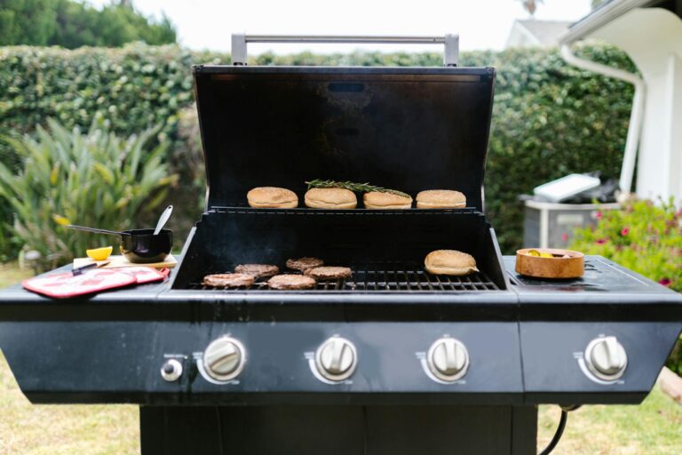 Outdoor barbecue grill with burgers and buns, perfect for summer cooking.
